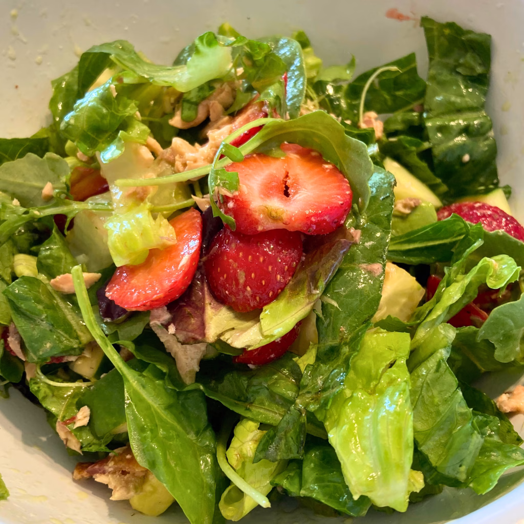 AIP summer salad with fresh strawberries, grilled chicken, cucumber slices, and a light lemon juice dressing served in a white bowl.